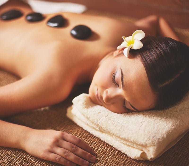 Masaje con piedras calientes en la espalda de mujer recostada en spa de Lindavista